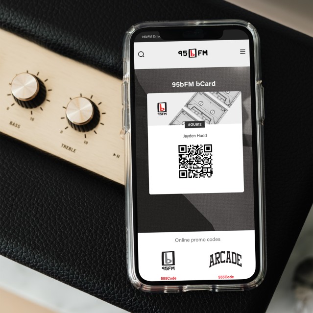 95bfm.com on a phone sitting on a guitar amp